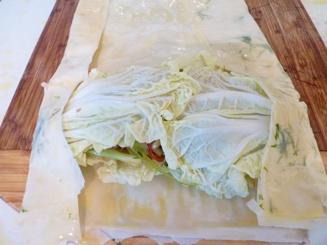 Carefully bring in the outer edges of the filo pastry and wrap around the ends of the fish and vegetable mixture and roll up from the end tucking in any loose pastry as you go. 